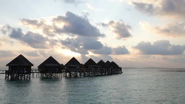 Trä väg från ön till en hydda över vattnet på en solnedgång. Maldiverna — Stockvideo