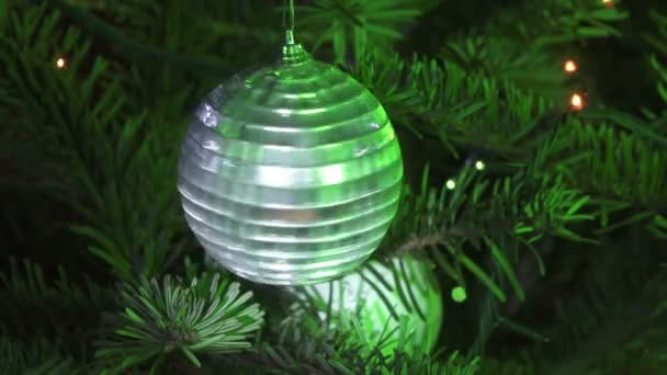 Новогодний зеркальный бал на фоне украшенного гирляндой новогодней елки — стоковое видео