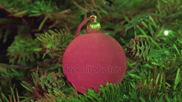 Bola roja de Año Nuevo sobre el fondo de la guirnalda decorada de un árbol de Navidad — Vídeos de Stock