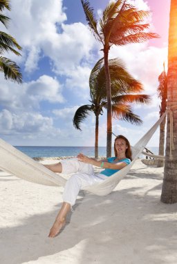 Arka plan mavi bir deniz üzerinde hamakta kadın