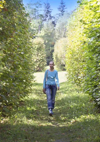 Femeia tânără într-o jachetă albastră merge în parcul de vară . — Fotografie, imagine de stoc