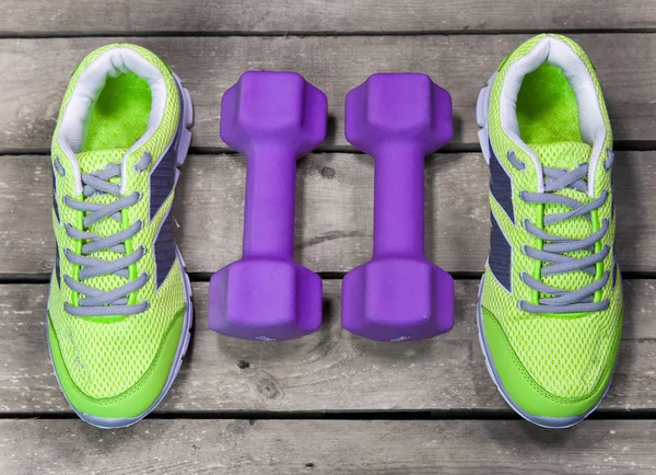 Sports sneakers, dumbbells, on a wooden background,  flat lay