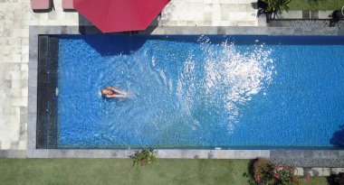 Genç güzel kadın havuzda düz yatıyordu, dron görünümü