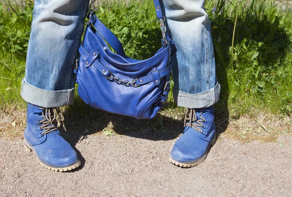 ブルー ジーンズとブーツを緑の芝生の夏の背景に青色の袋で女性の足 — ストック写真