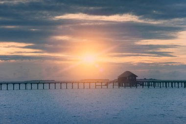 Siluet kulübe bir günbatımı üzerinde şeffaf sessiz deniz su üzerinde tonlama. Maldivler