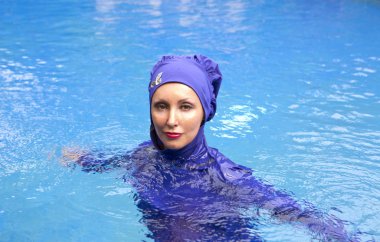 Müslüman mayo giymiş çekici bir kadın havuzda burkini giyiyor.