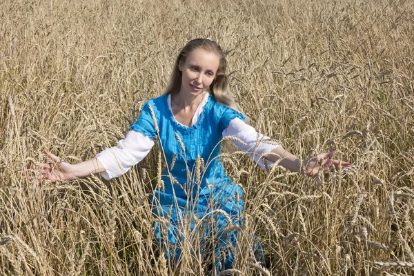穀物の熟した耳の分野で青いロングドレスで美しい女性 — ストック写真