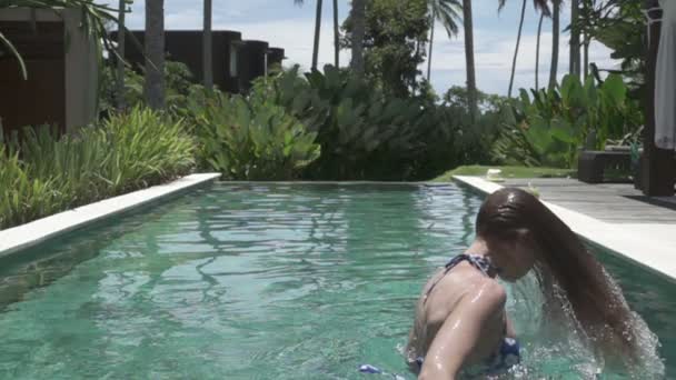 Slowmotion, jonge slanke vrouw in Bikin in het zwembad gooit lang natte haren in de tropische resort — Stockvideo