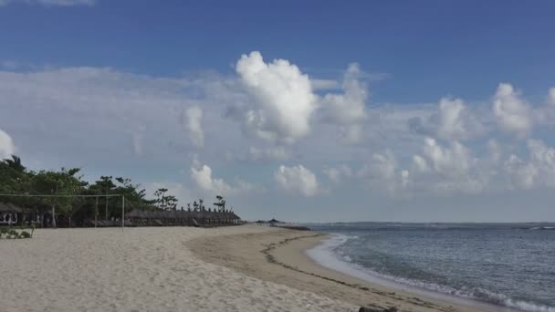 Blick auf den Sandstrand mit Liegestühlen und Sonnenschirmen im tropischen Resort. bali. Indonesien — Stockvideo