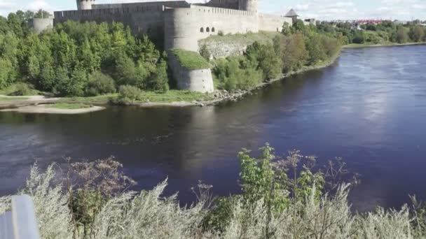Hermoso paisaje urbano, atracción turística medieval en la frontera rusa con Estonia, fortaleza de Ivangorod a orillas del río Narva, horizonte nublado del cielo — Vídeos de Stock