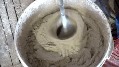 İnşaatçı, kuru inşaat karışımı, alçı, el yapımı karıştırıcı, onarım ve inşaat malzemelerini karıştırarak 4K Uhd 'da çekim yapıyor.