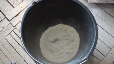 Hareket etmeyi kes. İnşaatçı duvar ustası kuru inşaat karışımını elle karıştırıcı ile yoğurmak için kaba atıyor. 4K Uhd 'da.