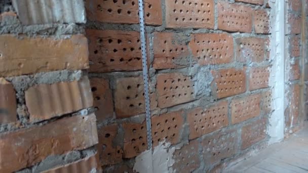 Gipsbouwer bevestigt bakens aan bakstenen muur om gipslaag aan te brengen, Reparatie en constructie, Schot in 4k Uhd — Stockvideo