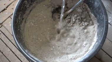 İnşaatçı suyu kuru inşaat karışımına doldurur ve el karıştırıcı, tamir ve inşaat ile yoğurur. 4K Uhd 'da.