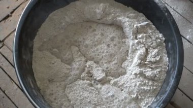 Hareket etmeyi kes, inşaatçı suyu kovayla kuru inşaat karışımına doldurur ve el karıştırıcı, tamir ve inşaatla yoğurur. 4k Uhd içinde.