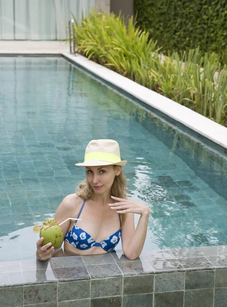 迷人的女人 留着长发 穿着泳衣 在游泳池里喝着椰子鸡尾酒 — 图库照片