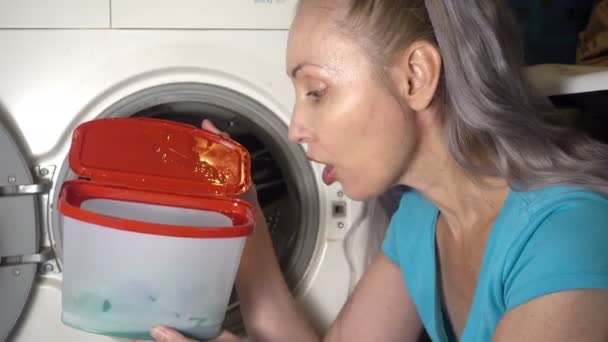 Young woman prepare to wash clothes in washing machine and takes out and opens box laundry washing agent And emotionally responds to fact that average for washing is not qualitative ,Shot in 4K UHD — Stock Video