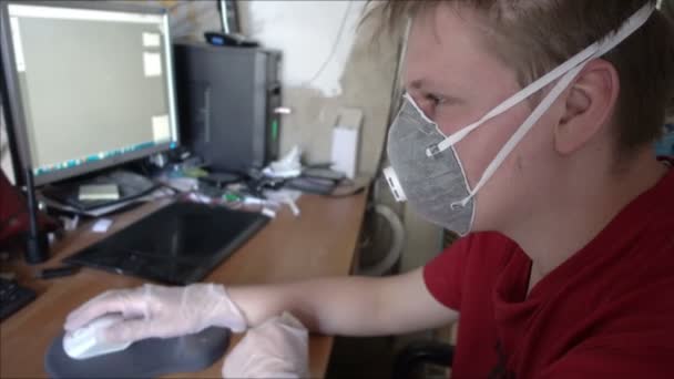 Fiatal férfi védőmaszkban és kesztyűben, otthonról dolgozik számítógéppel a koronavírus karantén miatt. — Stock videók