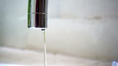 Açık havada eski kahverengi borudan kristal berrak su damlaları yavaşça düşüyor. Paslı musluğun tamire ihtiyacı var. Bulanık zemine yakın çekim su sıçrıyor. Hijyen için saf su. Döngü Videosu