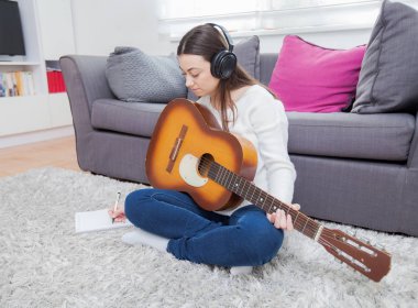Kadın akustik gitar çalıyor.