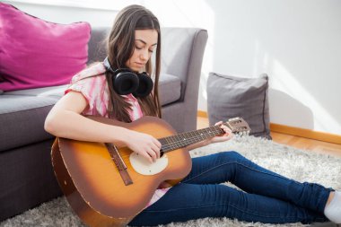 Akustik gitar, rahat kıyafetler evde katta oturan oynayan genç kadın