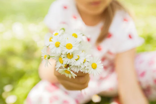 Happy little girl in nature with daisy bouquet at flower meadow, beautiful spring day
