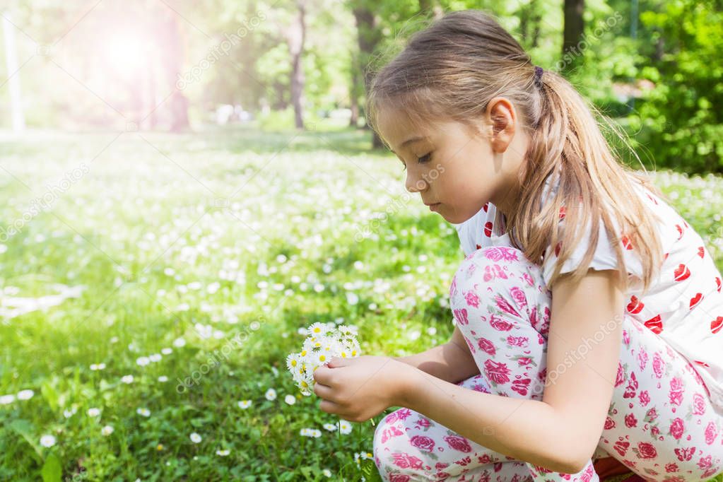 Happy little girl playing in nature at flower meadow, beautiful spring day 