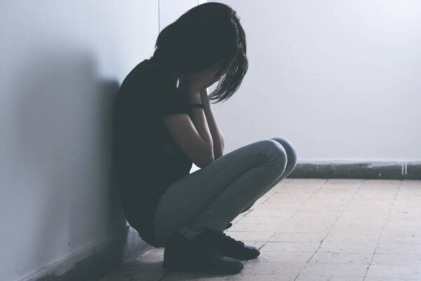 Depressed Teenager Girl sitting on the floor with hands cover face.