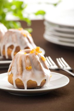 Beyaz tabakta Paskalya kek. İki çatal, daha fazla tabak ve kek içinde geçmiş. tüm üzerinde kahverengi masa örtüsü.