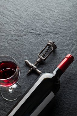 Bardağın yanında bir şişe şarap ve eski tirbuşon.