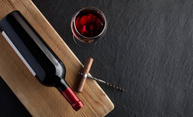 Tahtada şarap şişesi ve şarap kadehi var.