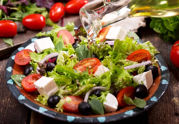 olive oil pouring into plate of salad