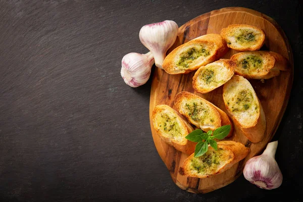 fresh garlic bread with herbs on a wooden board, top view