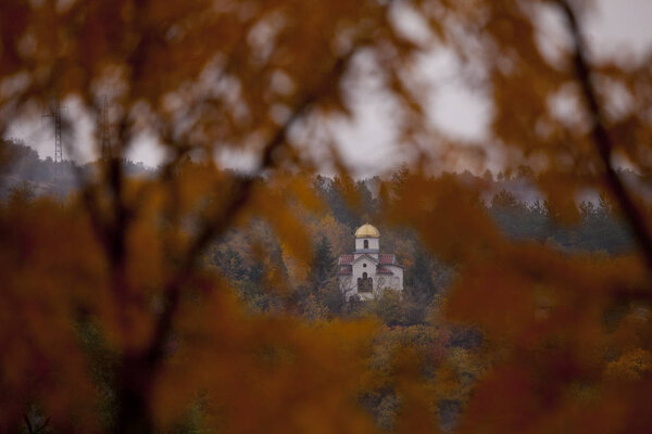 scenic shot of tranquil landscape with church in autumn forest