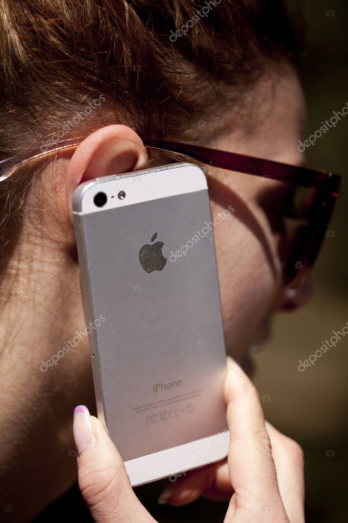 SOFIA, BULGARIA - APRIL 17, 2017: Woman talking with his Iphone sell phone.Selective focus on the Apple logo. iPhone was created and developed by the Apple inc.