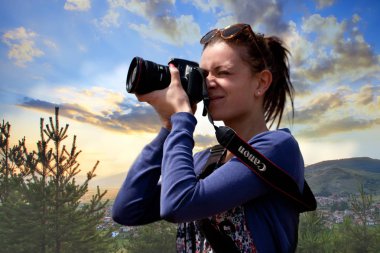 Sofia, Bulgaristan - 08 Mayıs 2017: Genç kız fotoğraf beatutiful doğa günbatımı sahne onun Canon kamera ve lens ile. Omzuna marka metin tarih seçici odak.