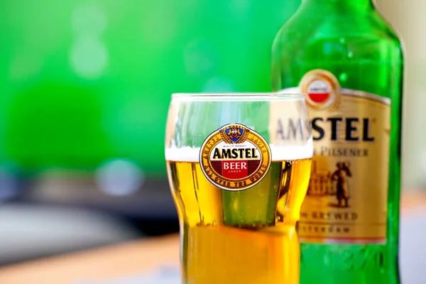 SOFIA, BULGÁRIA - MAIO 08, 2017: Amstel vidro e garrafa de fundo de tv jogando jogo de futebol.Amstel Premium Pilsener é uma marca internacionalmente conhecida de cerveja produzida pela Heineken International — Fotografia de Stock