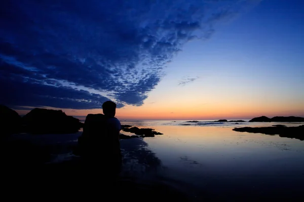 Waching człowiek piękny wschód słońca na skalistej plaży, na bułgarskim wybrzeżu Morza Czarnego krajobraz — Zdjęcie stockowe