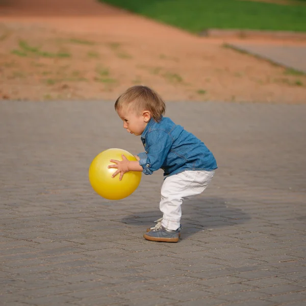 Liten pojke leker med gul boll — Stockfoto