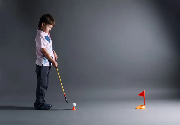 Маленький мальчик играет в мини-гольф — стоковое фото