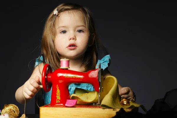 Niña está jugando con la máquina de coser —  Fotos de Stock