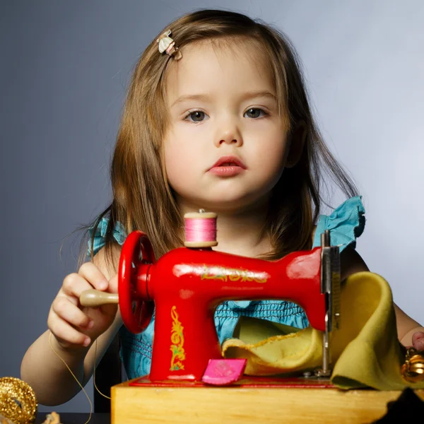 Little girl is playing with sewing machine — Stock Photo, Image