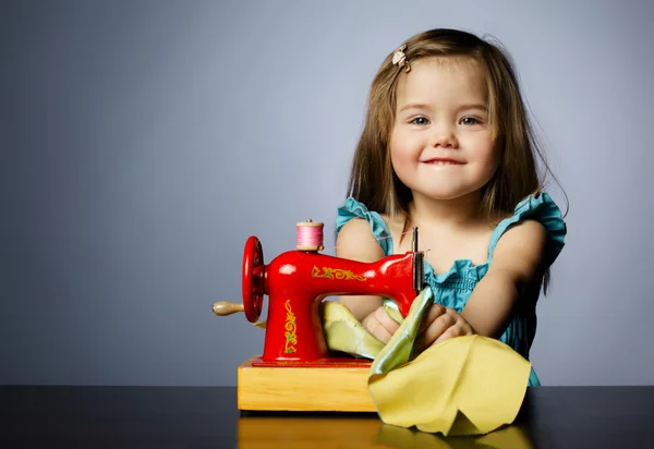 Küçük kız dikiş makinesi ile oynuyor — Stok fotoğraf
