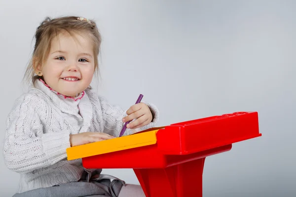 Улыбающаяся маленькая девочка за столом — стоковое фото