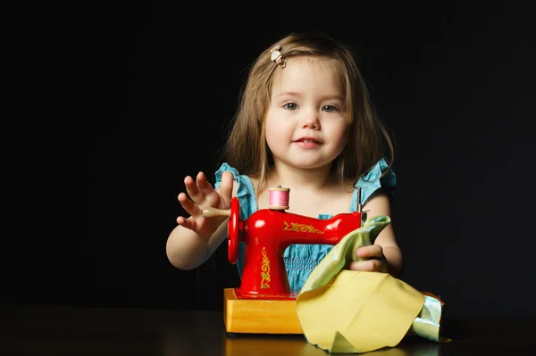 Menina está brincando com a máquina de costura — Fotografia de Stock