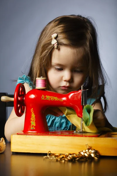 Malá holčička se hraje s šicí stroj — Stock fotografie