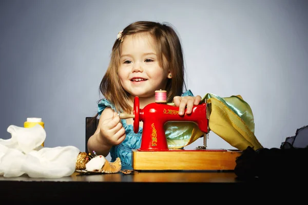 Menina está brincando com a máquina de costura — Fotografia de Stock