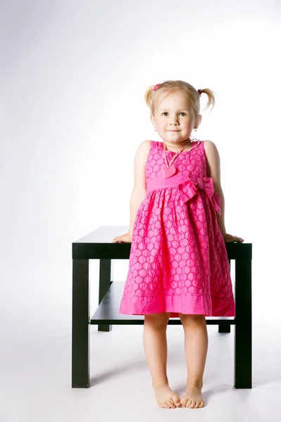 Cute little girl sitting on table — Stock Photo, Image