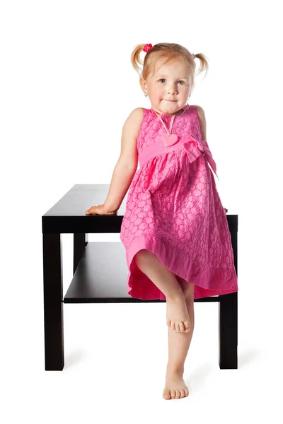 Cute little girl sitting on table — Stock Photo, Image