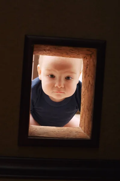 Маленький ребенок смотрит на дыру в стене — стоковое фото
